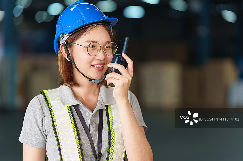 在工厂仓库内的物流行业工作的年轻女仓储工人。泰国女仓储工人在工厂仓库行业进行检查图片素材