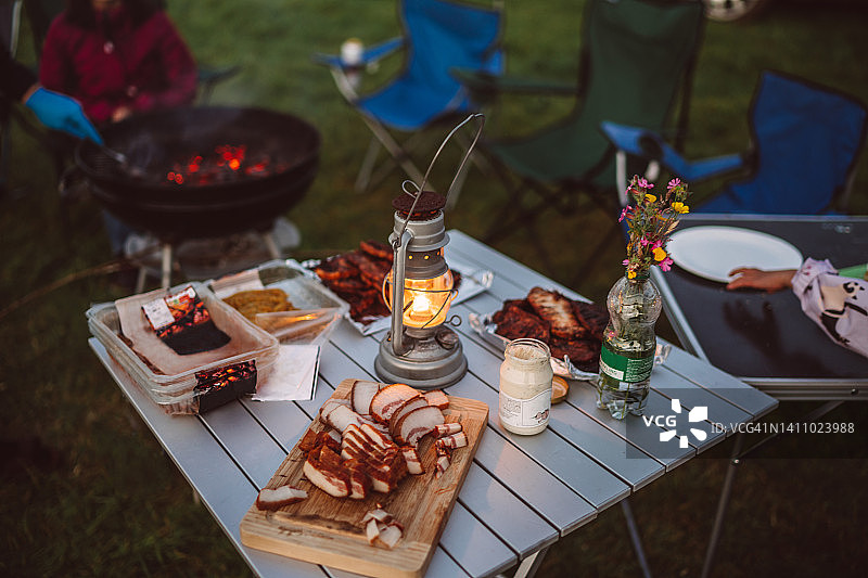 户外野餐桌上的肉拼盘与油灯图片素材