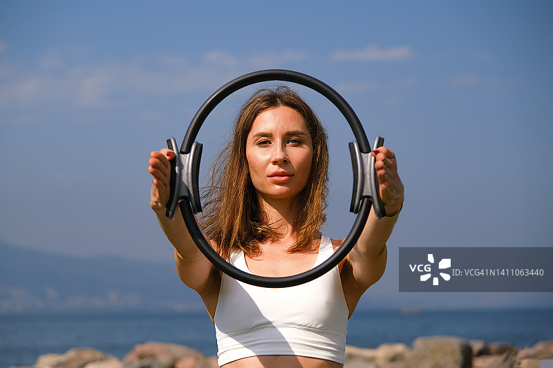 年轻普拉提教练在户外用健身环进行运动练习图片素材