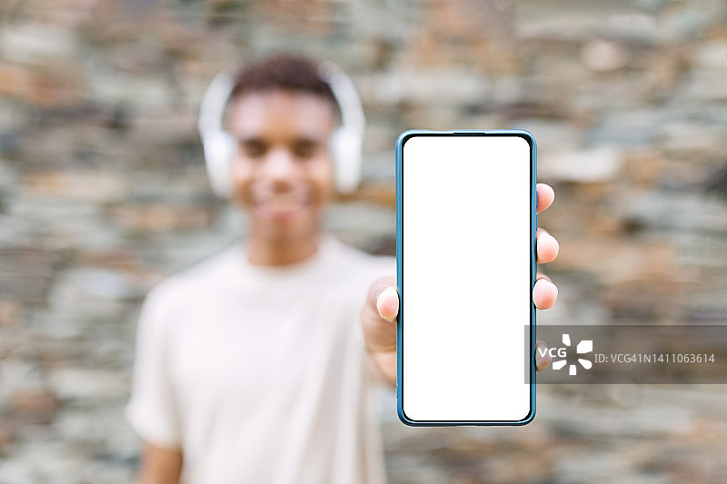 快乐的年轻人手持带有白色空白竖版的智能手机图片素材