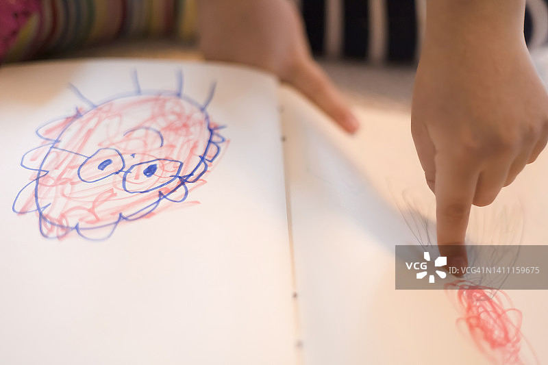 年轻混血女孩在笔记本上画简笔画图片素材