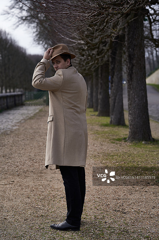 米色外套的英俊男士在巴黎公园散步图片素材