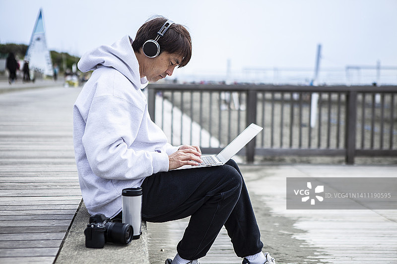 在海滩上使用笔记本电脑的日本男人图片素材