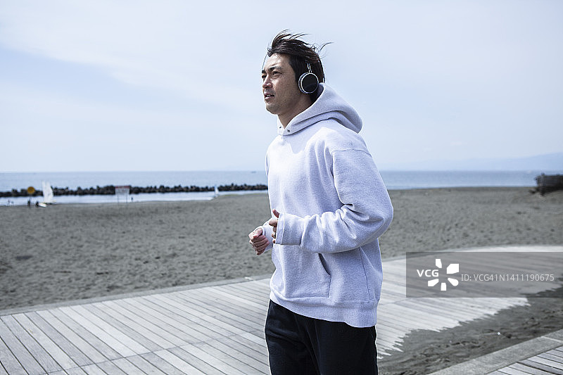 戴着耳机在海边跑步的男人图片素材