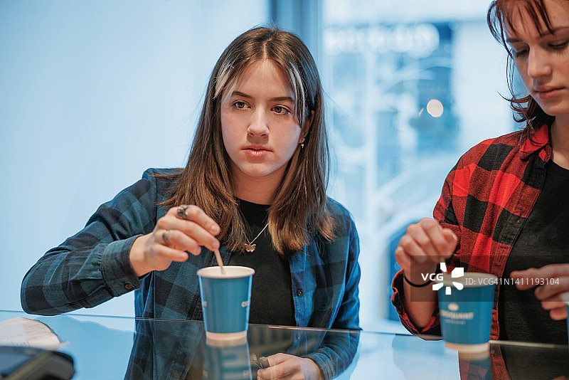 自助餐厅柜台前搅拌咖啡的少女图片素材