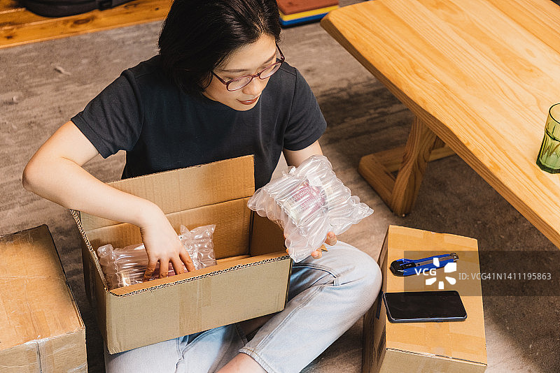 亚洲女人拆开网上订购的包裹图片素材