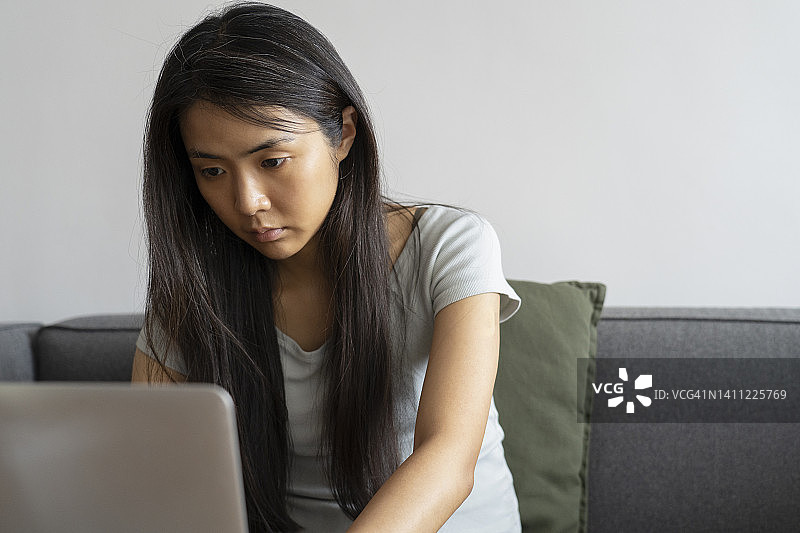 亚洲年轻女子用笔记本电脑工作的中景照片图片素材