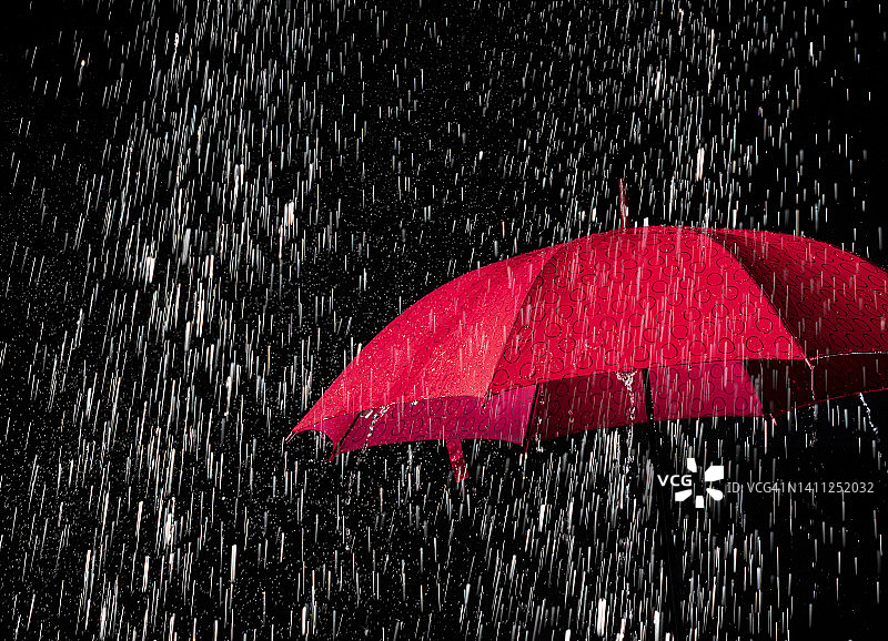 黑色背景上空雨滴落下的打开的雨伞图片素材