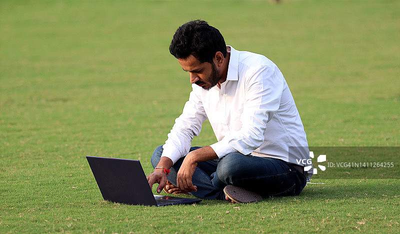 在户外使用笔记本电脑的年轻男人图片素材