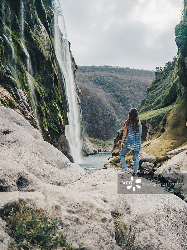 年轻女子在瀑布附近的河岸边小憩图片素材