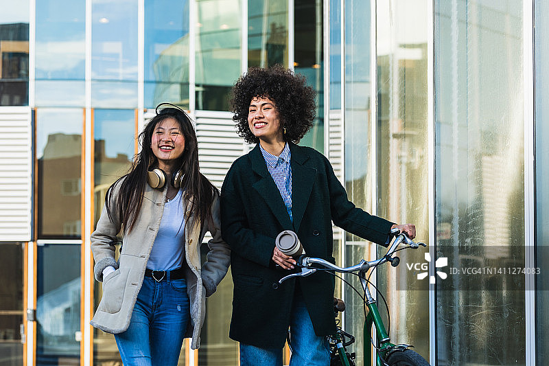清晨，穿着牛仔裤和夹克的女性同事到达办公大楼图片素材