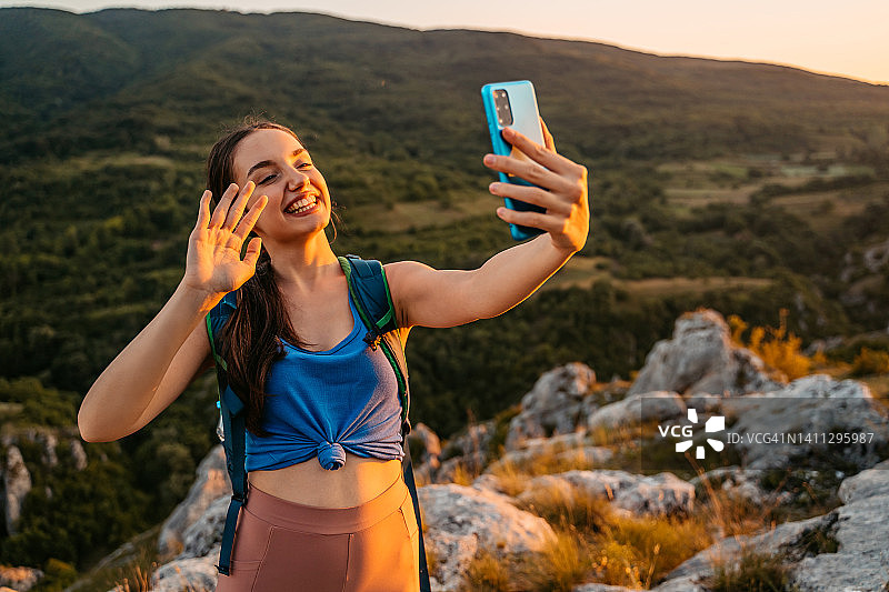 年轻女人在山上徒步时进行视频通话图片素材