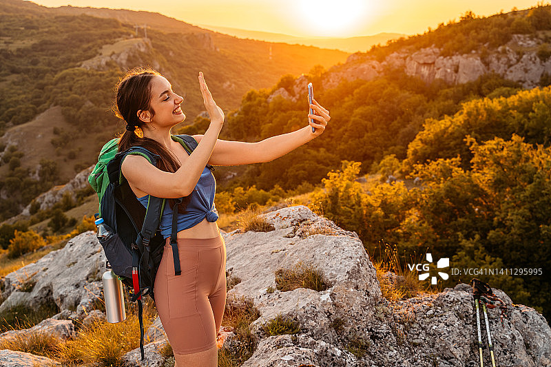 年轻女人在山上徒步时进行视频通话图片素材