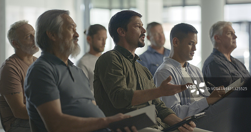 办公室研讨会：与会者交流笔记，男性企业家学习商业策略，会议听众图片素材
