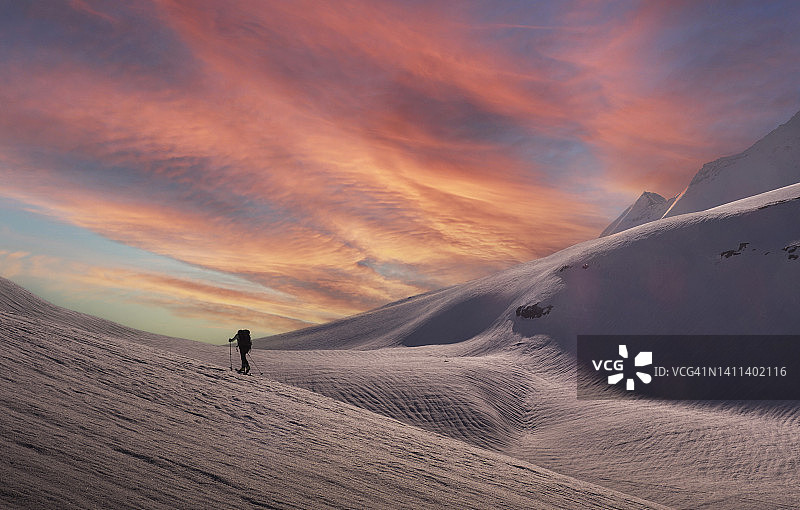 日出时分雪坡上的登山者图片素材