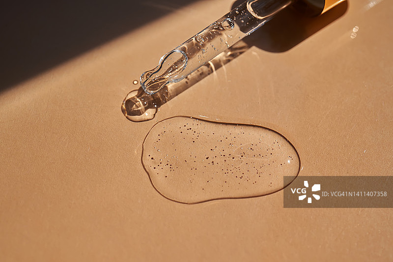 米色背景上的化妆品滴管和化妆品油或精华液图片素材