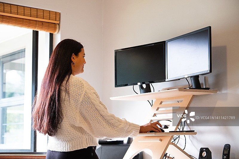 在站立式办公桌前使用台式电脑的女人图片素材