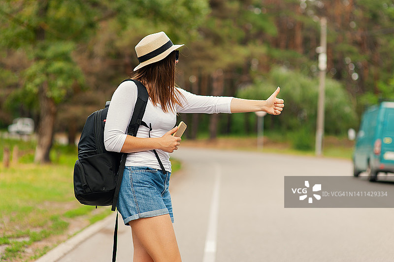 年轻女游客在路上用手机打车图片素材