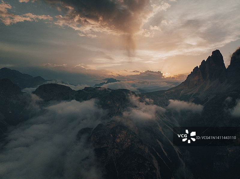 意大利多洛米蒂山三峰边缘被云覆盖的山谷日落图片素材