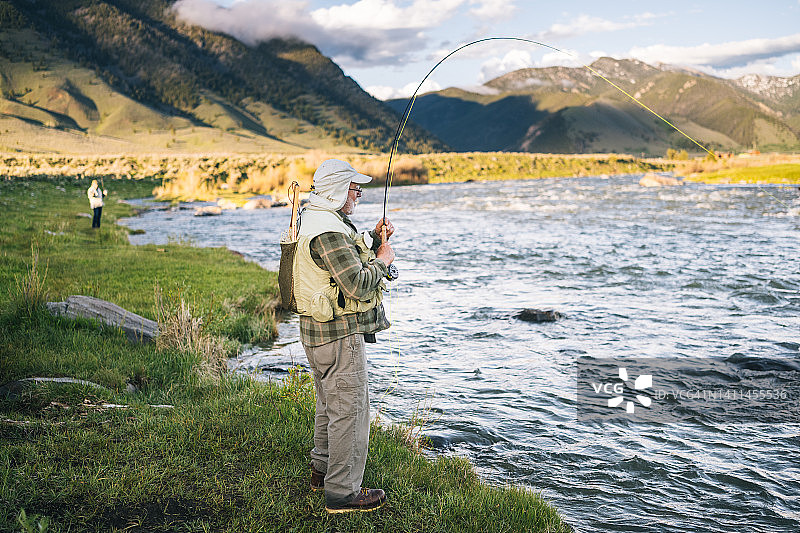 在野河岸边飞蝇钓鱼的钓鱼人图片素材