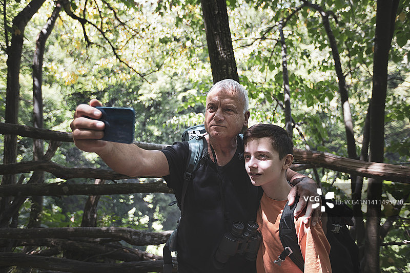 爷爷和孙子在森林里散步时自拍图片素材