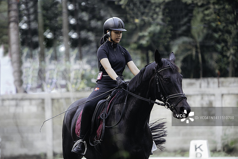 一位年轻女子和她美丽的年轻公马一起表演伸长步图片素材
