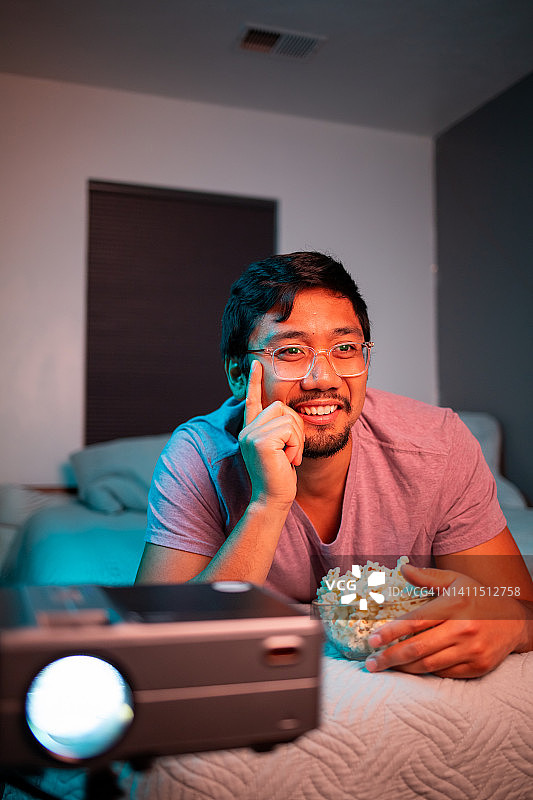 男子在床上用投影仪看电影图片素材