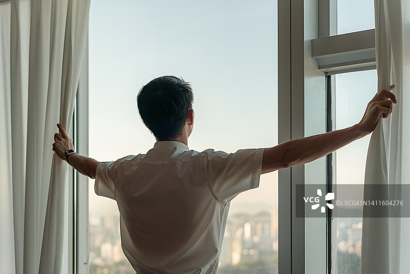 男人拉开窗帘图片素材