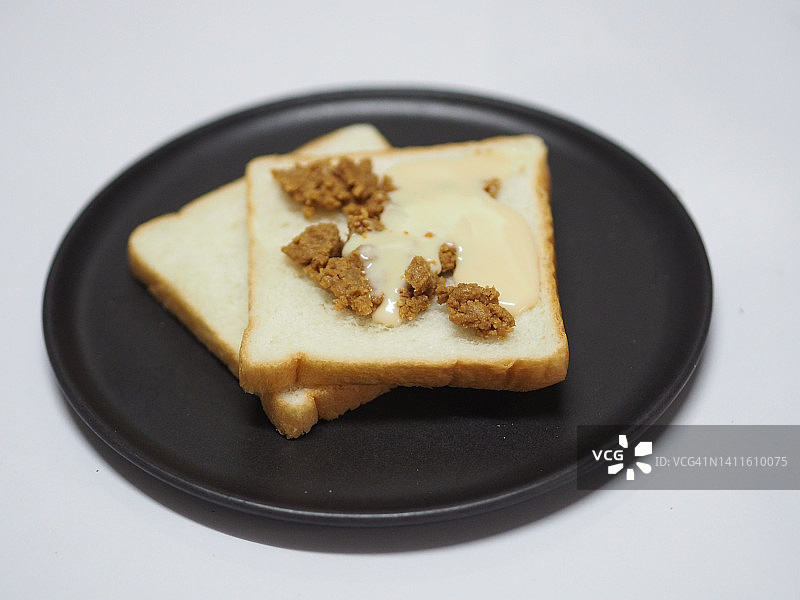加花生酱的炼乳面包，放在黑色盘子上图片素材