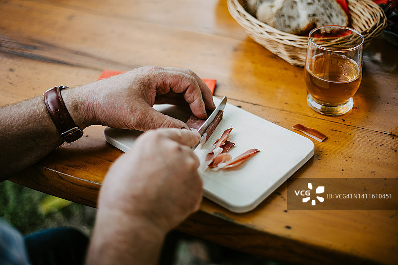 男子在木板上切割黑森林火腿图片素材