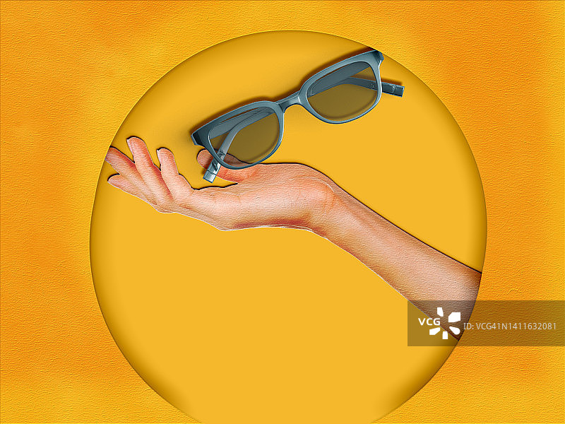 女性手持绿色太阳镜的数字合成图像（黄色背景）图片素材