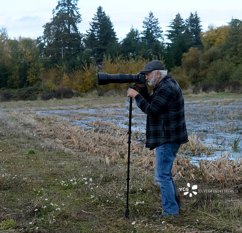 站在加拿大不列颠哥伦比亚省田野里用三脚架拍照的男人图片素材