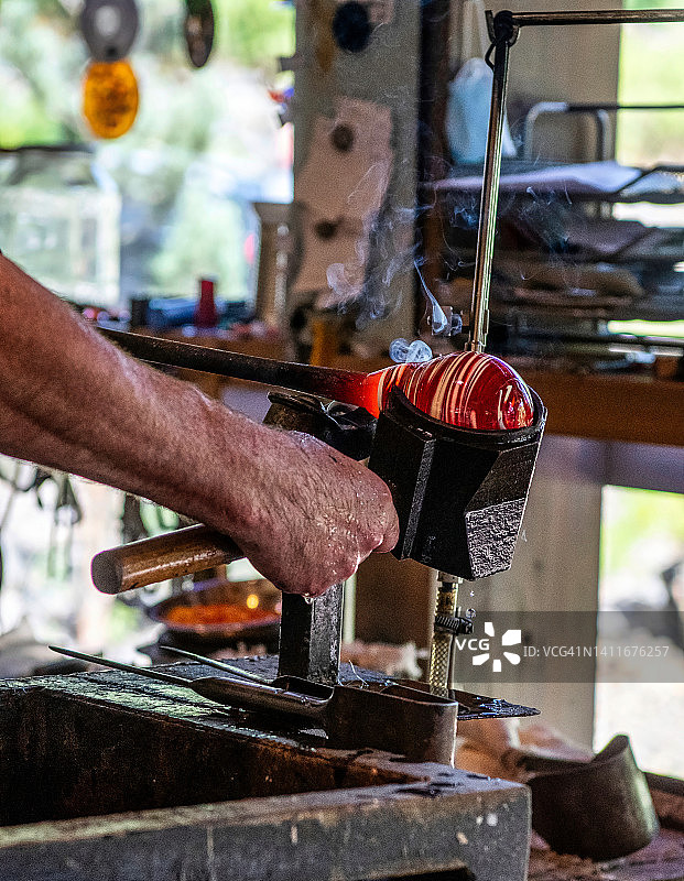 工匠在工作室中塑造熔融玻璃图片素材