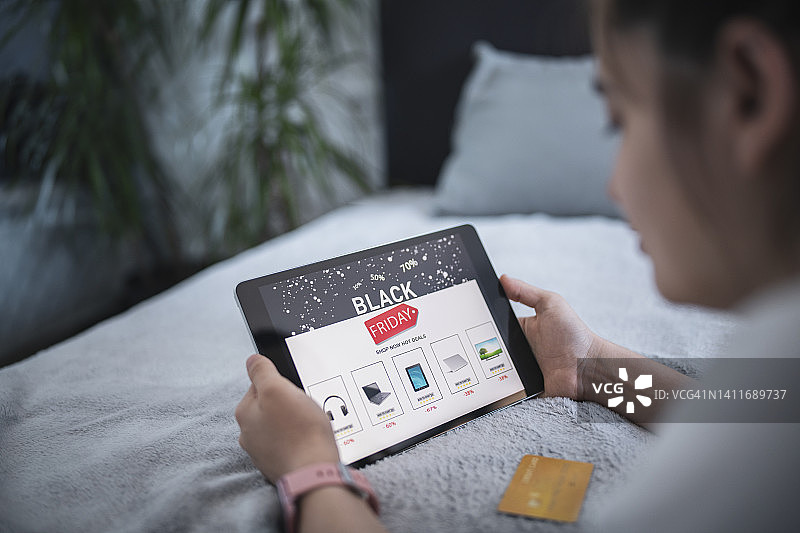 女人躺在床上用平板电脑网上购物图片素材