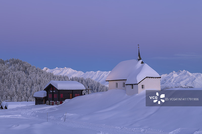 瑞士贝特默阿尔卑，村庄中心玛丽亚雪教堂的日落冬景图片素材
