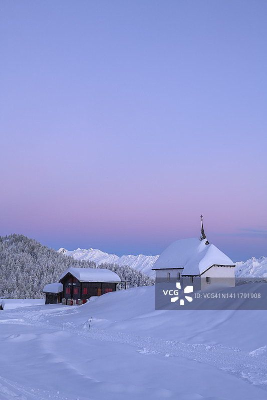 瑞士贝特默阿尔卑，村庄中心玛丽亚雪教堂的日落冬景图片素材