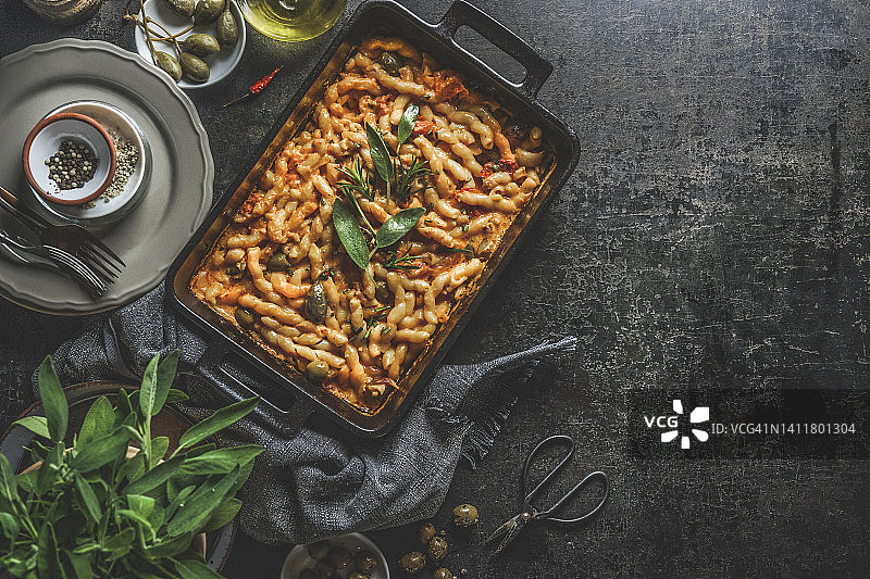 自制地中海砂锅意面，番茄酱和橄榄，搭配餐盘、新鲜香草和厨具图片素材