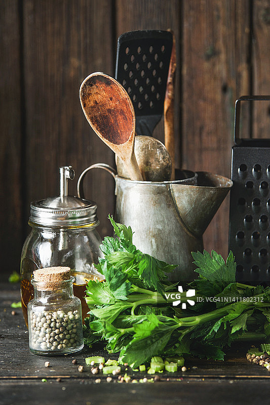 复古厨房用具静物，包括木制烹饪勺、磨碎器、牛奶罐、玻璃罐和乡村木制厨房桌上的食材图片素材