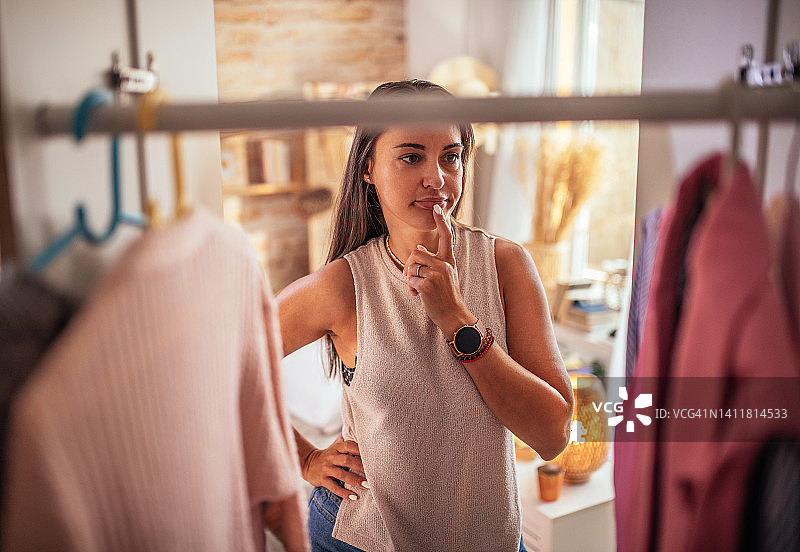 年轻女人从衣柜里拿出衣服试穿图片素材