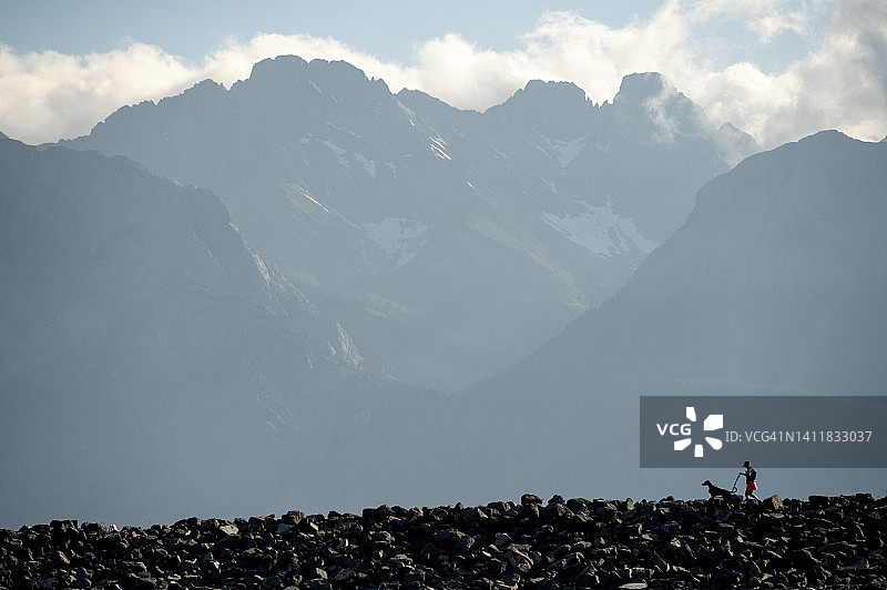 徒步旅行的女性和狗在山脊上的景色图片素材