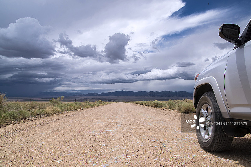 科罗拉多州，暴风云地平线下，行驶在漫长笔直砾石路上的汽车图片素材