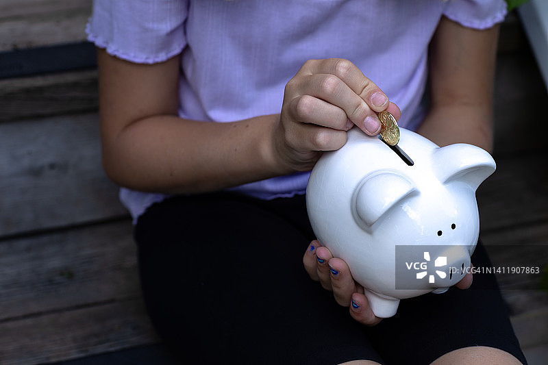 孩子往储蓄罐里投金币（身份不明）图片素材
