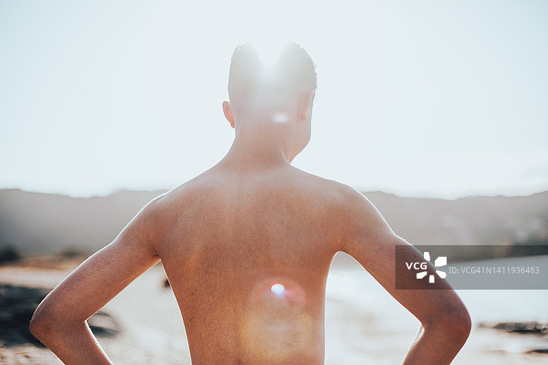 海滩上的年轻男子背影人像，光线柔和图片素材