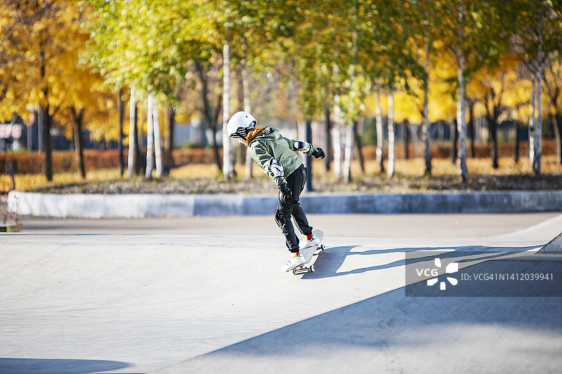 男孩在秋季滑板公园玩滑板图片素材