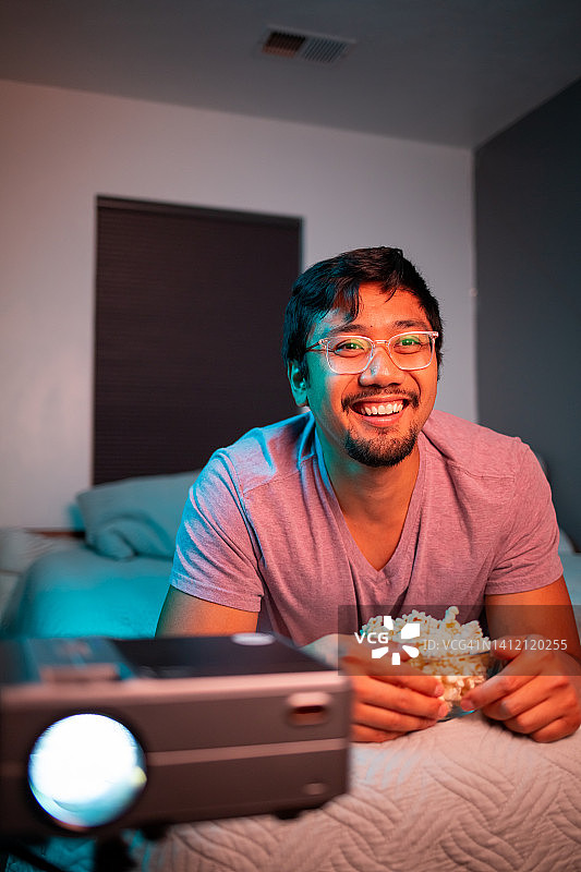 在床上用投影仪看电影的男人图片素材