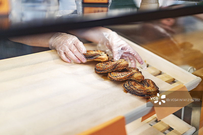 戴手套的手从托盘中取出新鲜面包图片素材