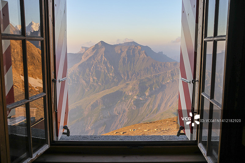 在日落时分从山间小屋的窗户向外看，瑞士阿尔卑斯山图片素材