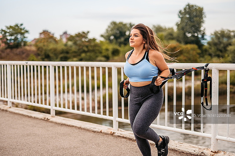 在桥上用阻力带锻炼的年轻女子图片素材