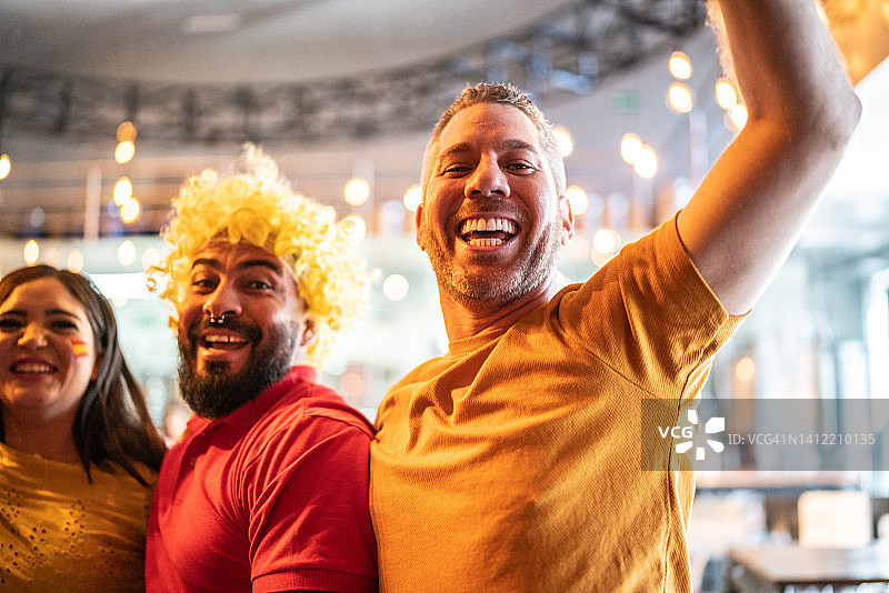 在酒吧观看足球比赛并庆祝的西班牙朋友图片素材