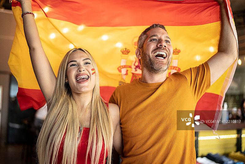朋友们在观看足球比赛，并挥舞着西班牙国旗庆祝图片素材